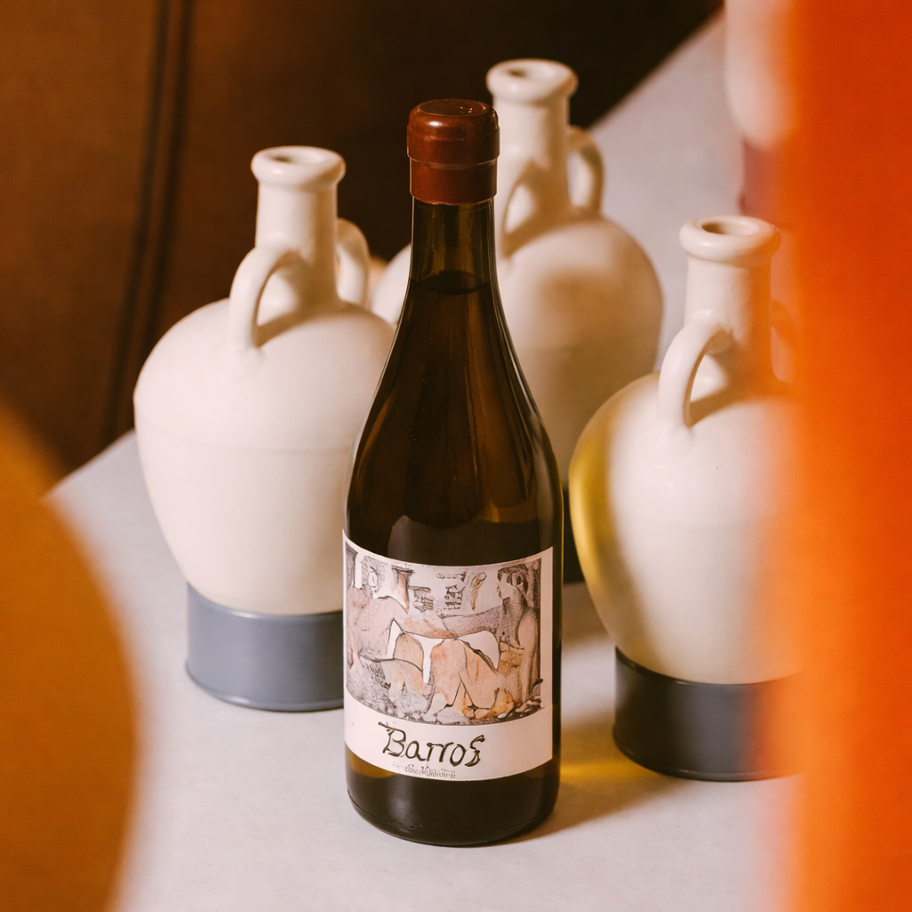 Botella de vino blanco Barros de Cecili de Bodegas Can Vidalet con etiqueta artística, rodeada de cerámica mediterránea en un ambiente cálido y elegante.