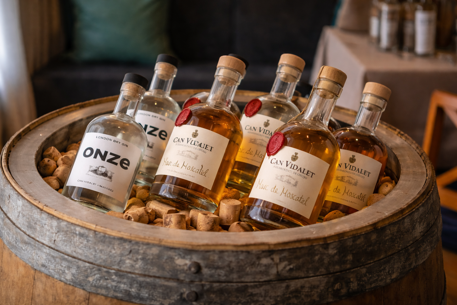 Botellas de ginebra Onze, Marc de Cecili y Marc de Moscatel de Can Vidalet en un barril con corchos. Destilados artesanales elaborados en Mallorca.