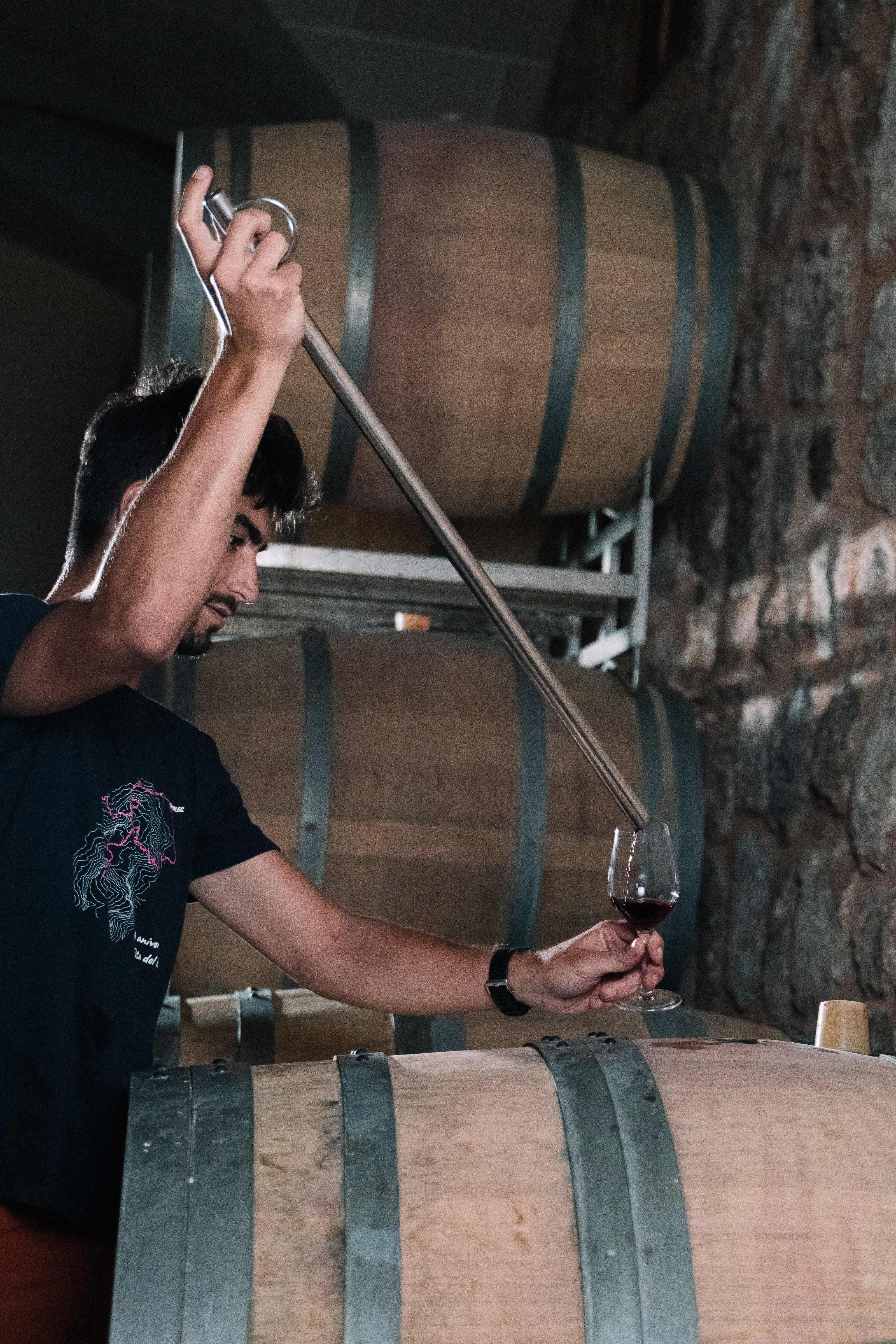 Enólogo extrayendo vino tinto directamente de una barrica de roble en la bodega Can Vidalet, en Pollença, Mallorca. La imagen muestra el proceso artesanal de control de calidad y envejecimiento del vino, destacando la dedicación y la tradición vitivinícola mallorquina.