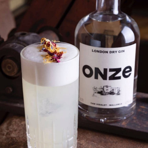 Gin Onze de Can Vidalet junto a un cóctel con espuma floral, perfecto para descubrir la esencia mallorquina en combinados sofisticados.