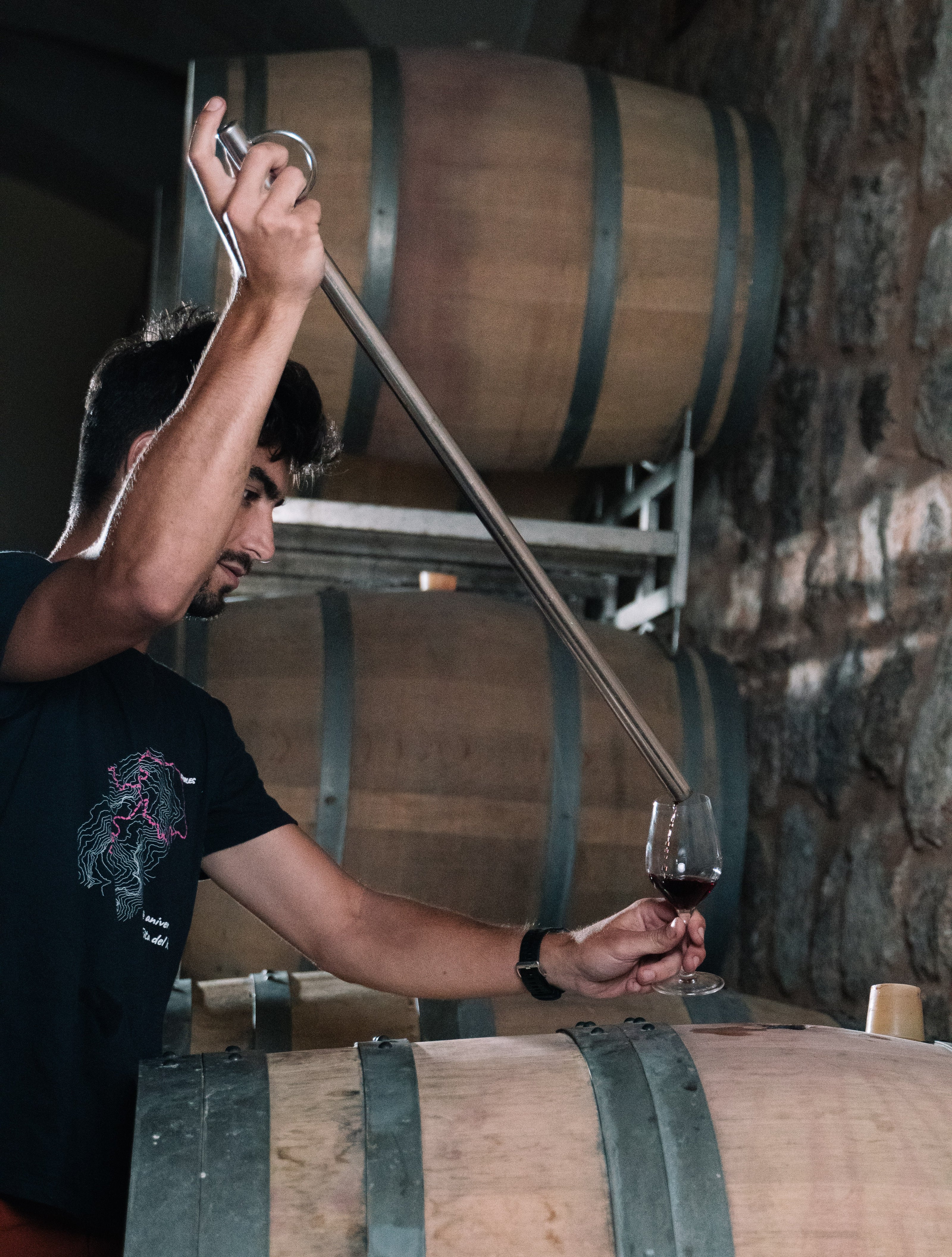 Enólogo extrayendo vino tinto directamente de una barrica de roble en la bodega Can Vidalet, en Pollença, Mallorca. La imagen muestra el proceso artesanal de control de calidad y envejecimiento del vino, destacando la dedicación y la tradición vitivinícola mallorquina.