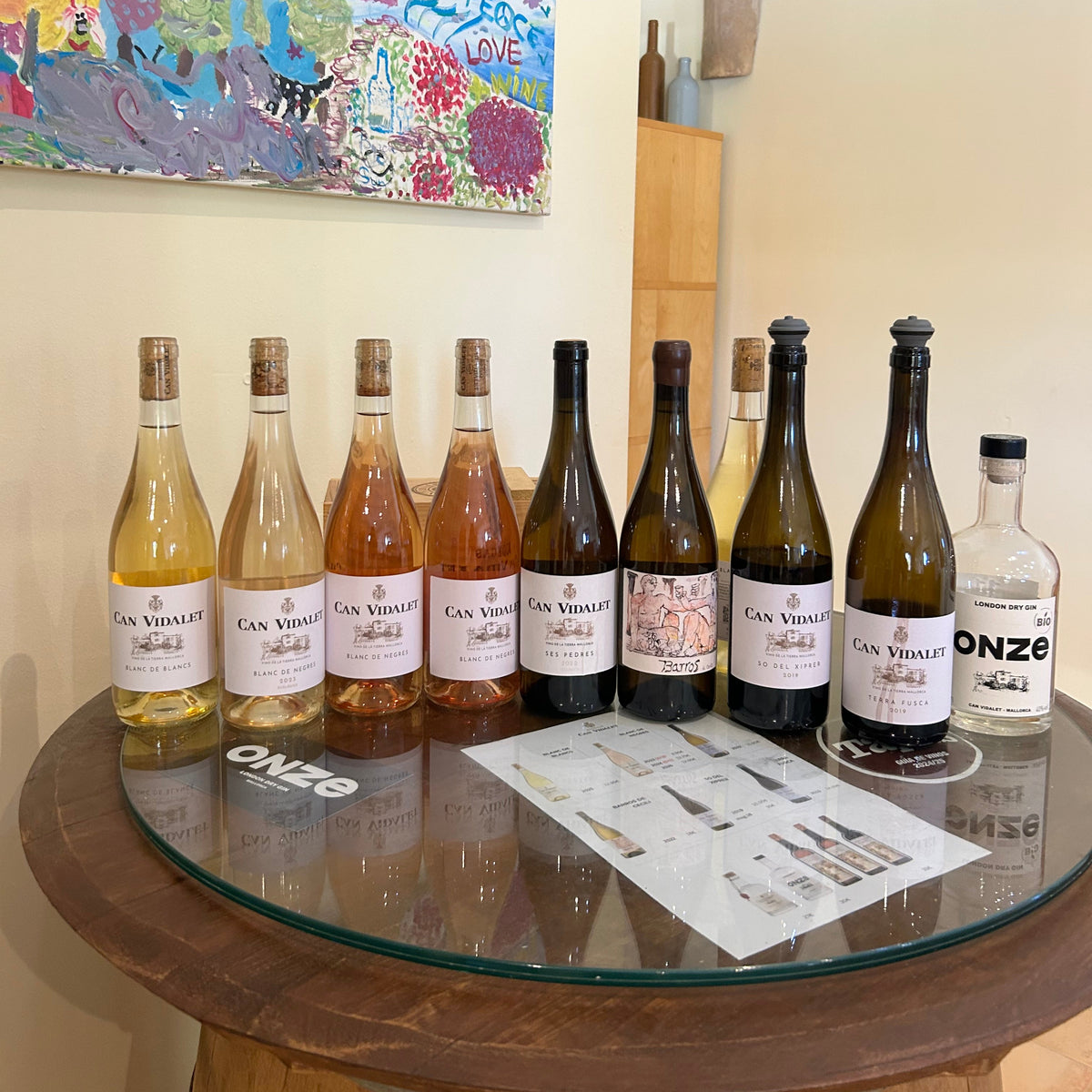Selection of Can Vidalet white, rosé and red wines displayed on a wooden table inside the winery.